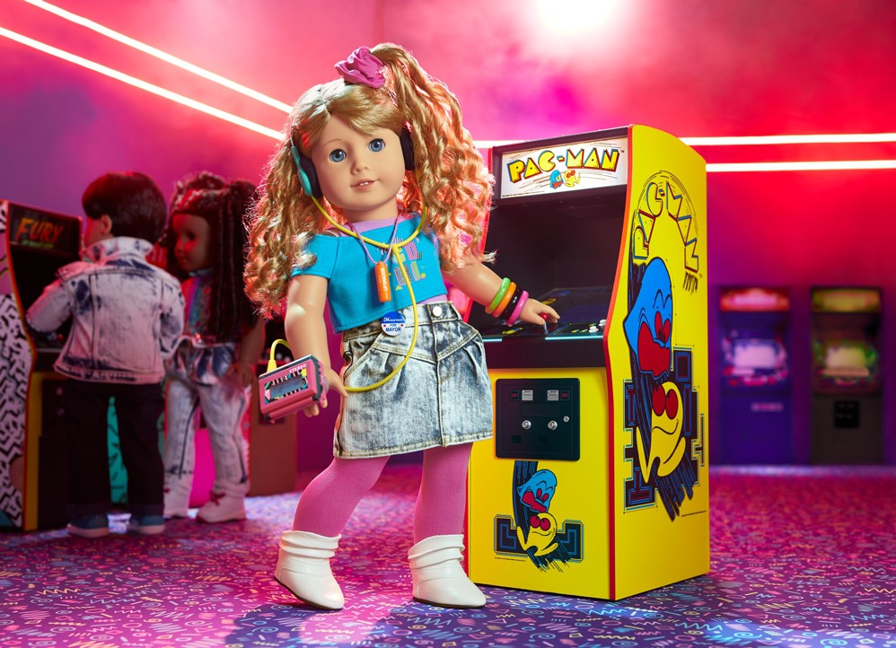 American Girl doll Courtney Moore posed in front of a doll-sized Pac-Man machine