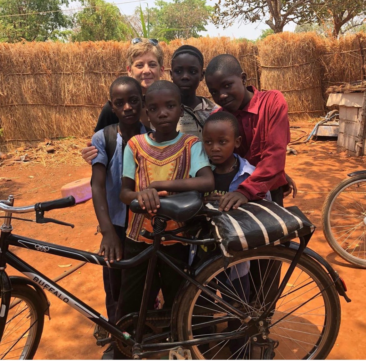 Durkin with children in Zambia posing next to a bicycle
