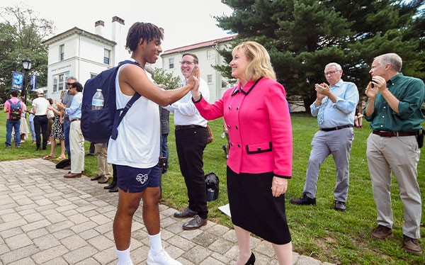 Susan Aldridge giving a high five to a student on campus