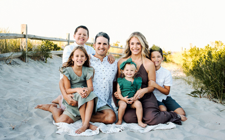 Rendfrey smiling with his family on the beach