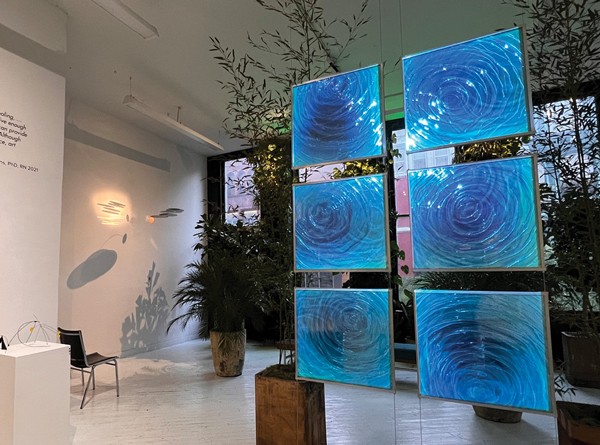 Art exhibit in a waiting room with six floating, square paintings that are textured and blue