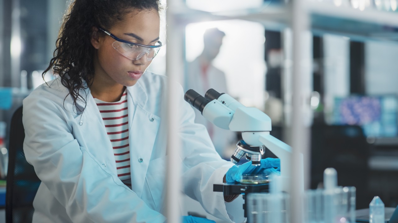 Medical Science Laboratory: Portrait of Beautiful Black Scientist Using Microscope, Does Analysis of Test Sample. Ambitious Young Biotechnology Specialist, working with Advanced Equipment